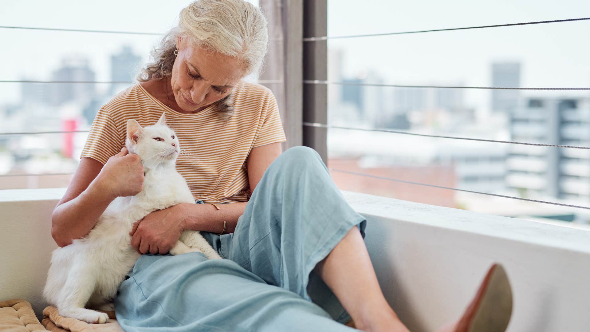 woman petting cat sitting outside