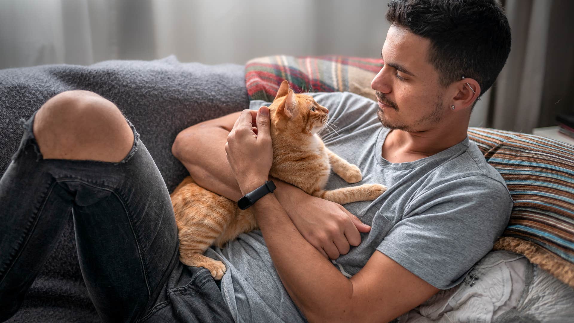 man cuddling with cat on the couch
