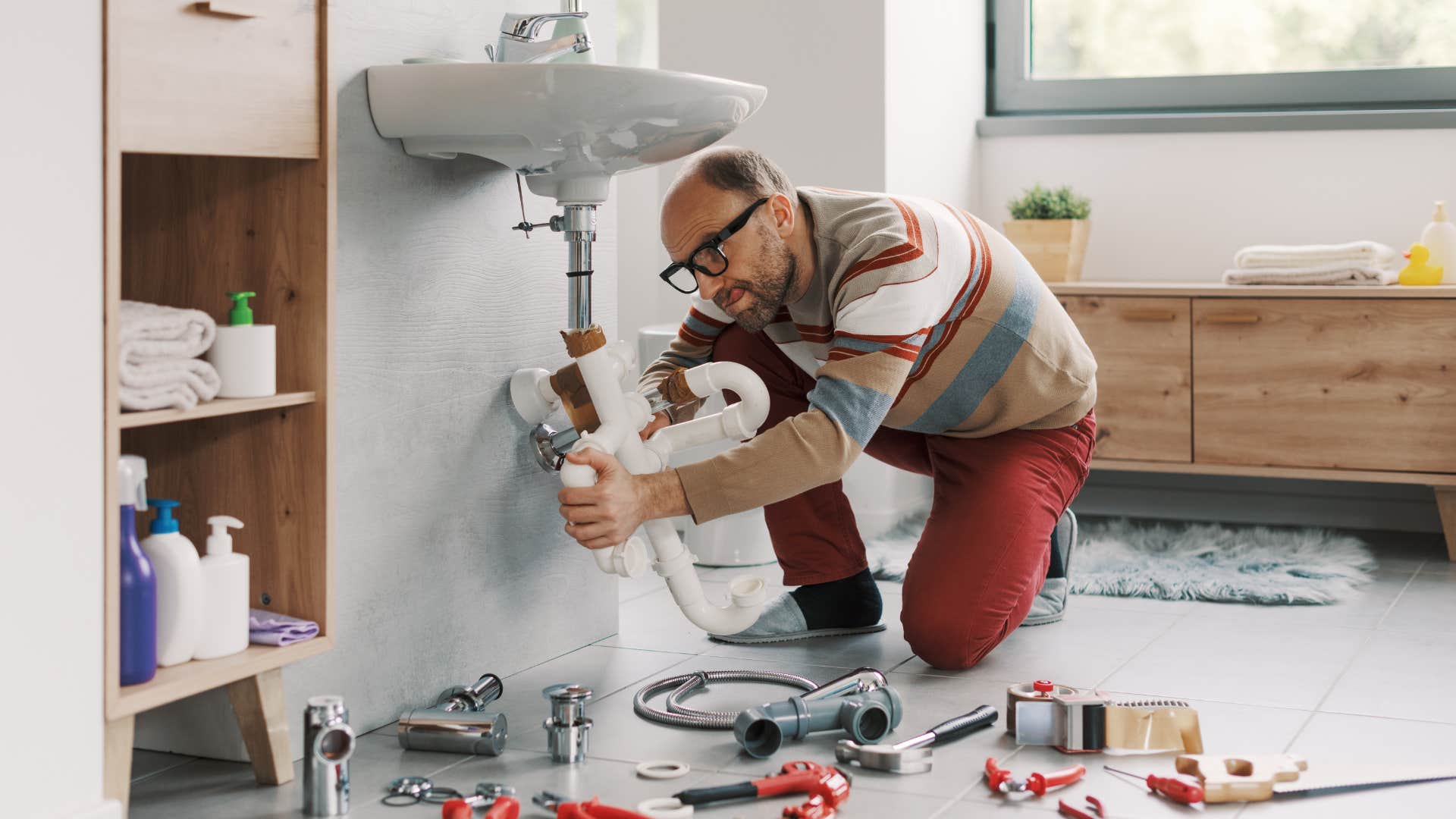 man fixing sink in bathroom