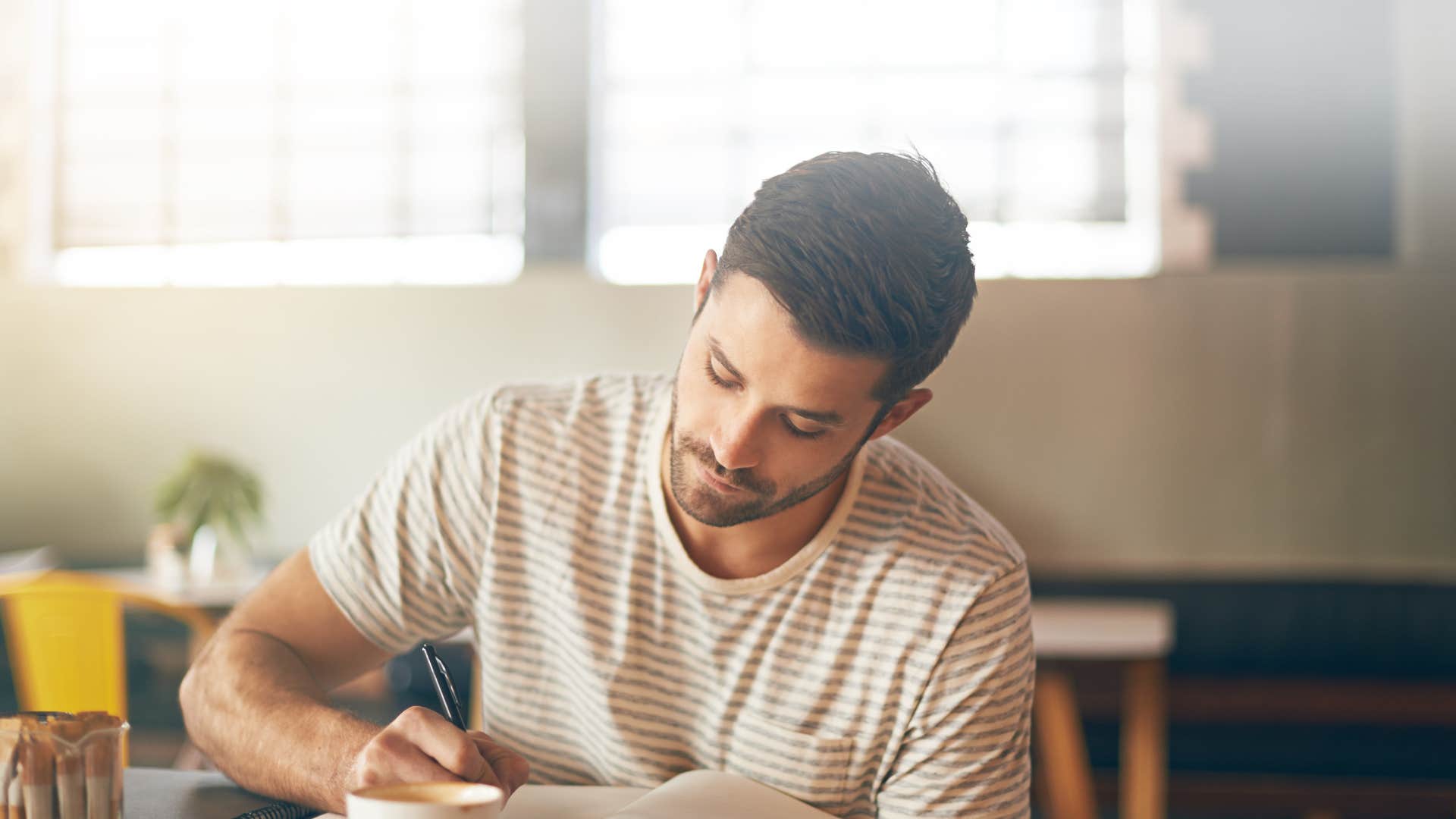 man writing poetry in notebook