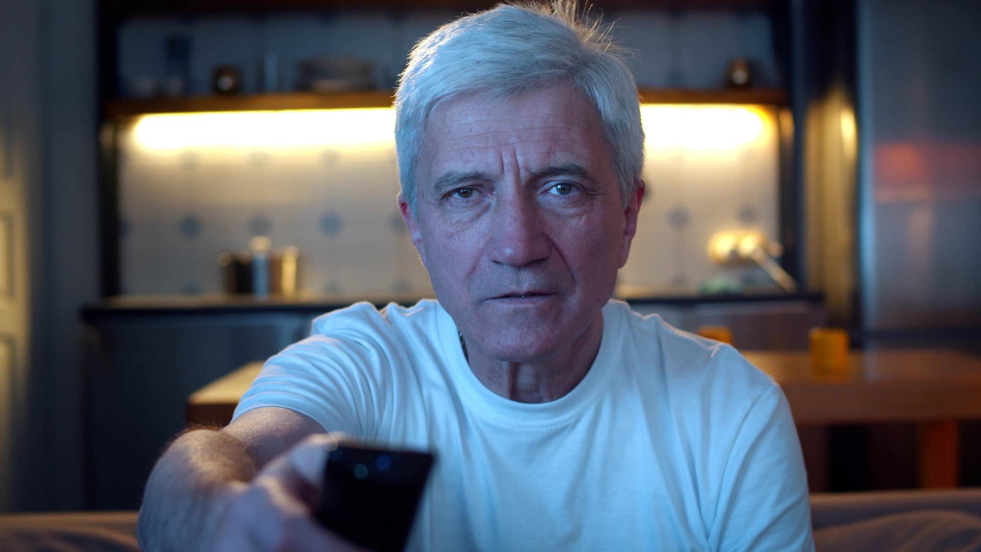 man watching television using remote control