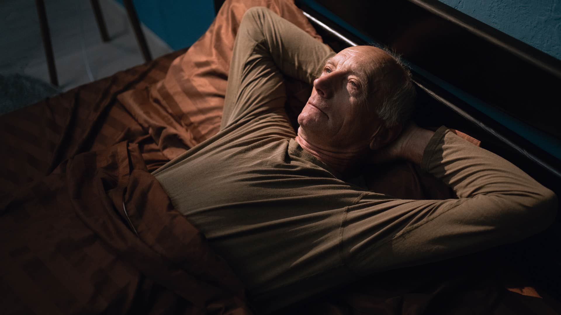 older man who stays up late lying awake in bed