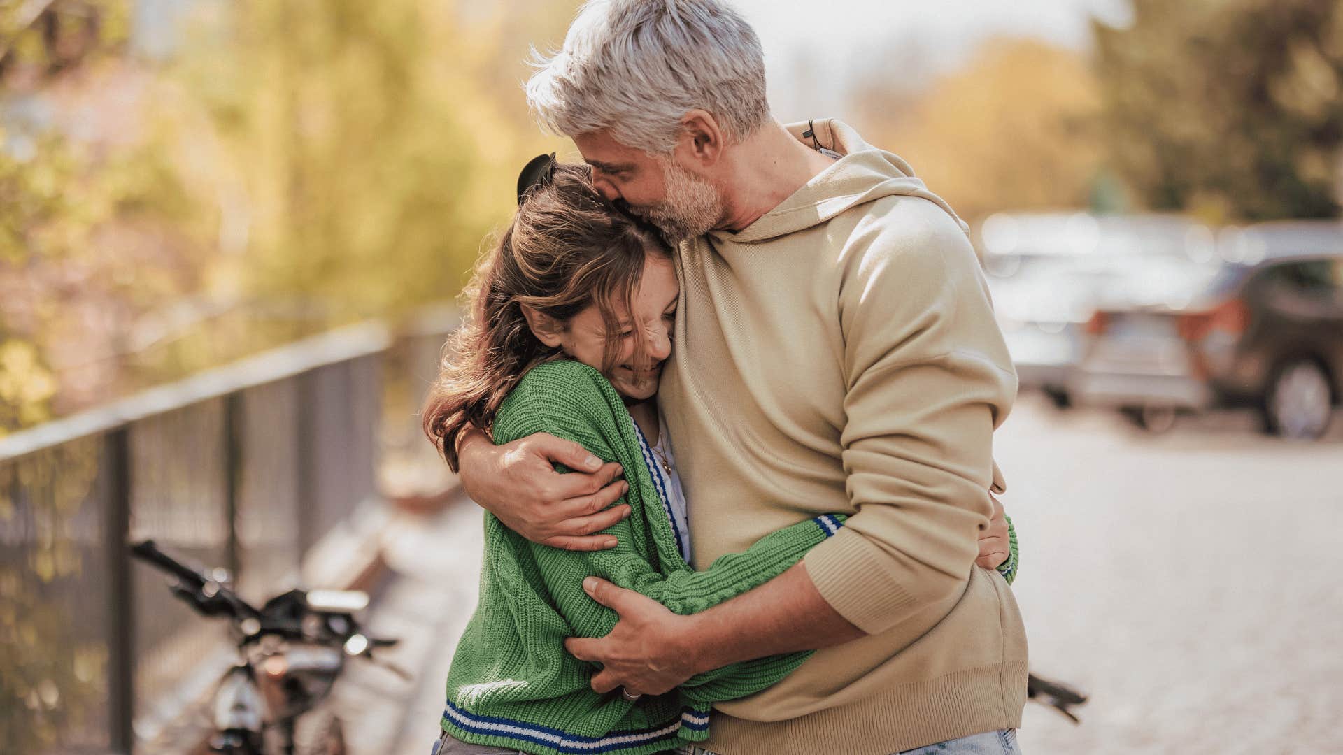 father hugging teen daughter kissing her head