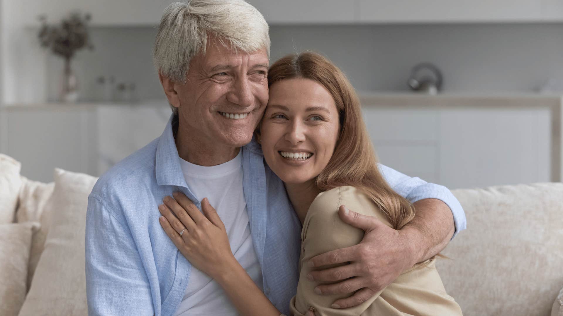 older father hugging adult daughter at home