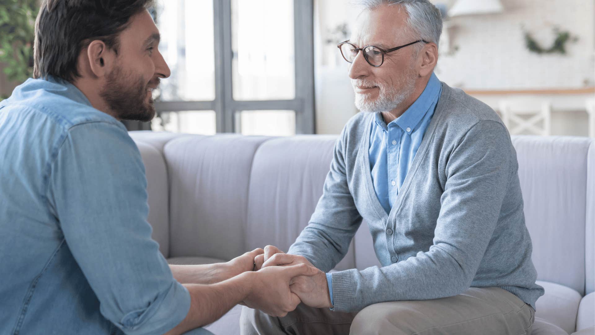 concerned father holding adult sons hands