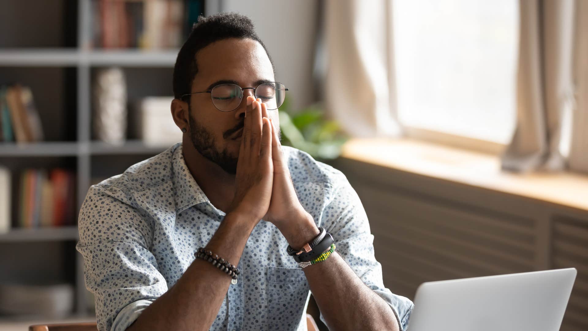 man praying at his laptop