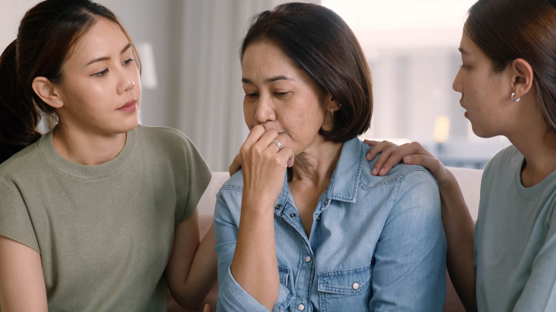 adult daughters comforting older mom
