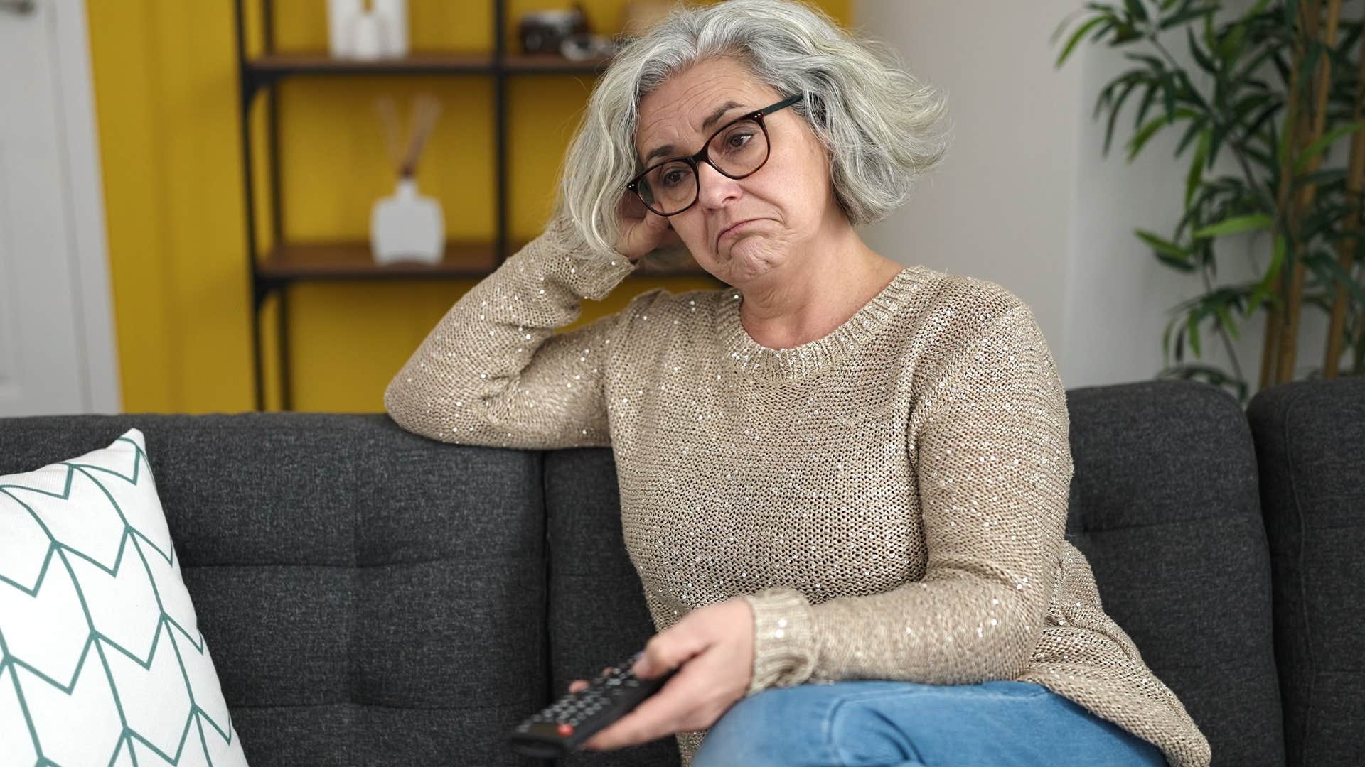 older woman watching tv at home alone