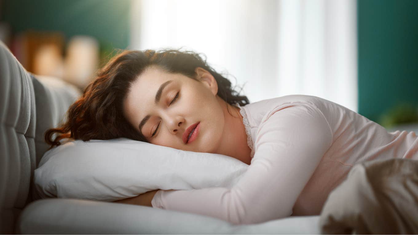 peaceful woman sleeping in bed with window open in background