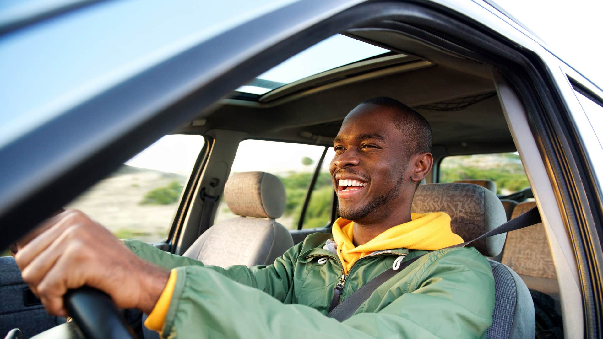 man driving car smiling happily as it has new upgrades and accessories
