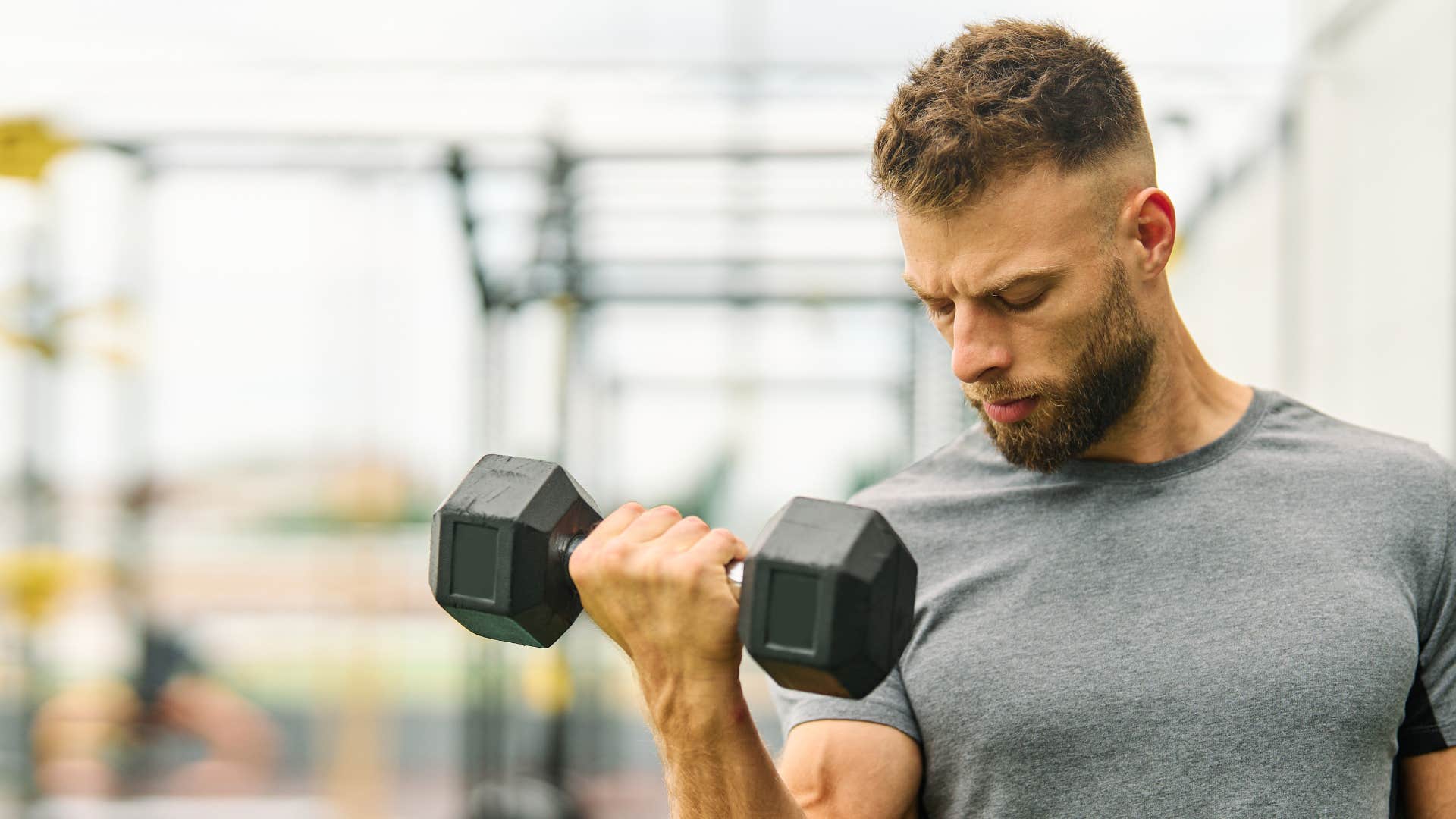man in gray shirt using fitness equipment and gym membership to exercise