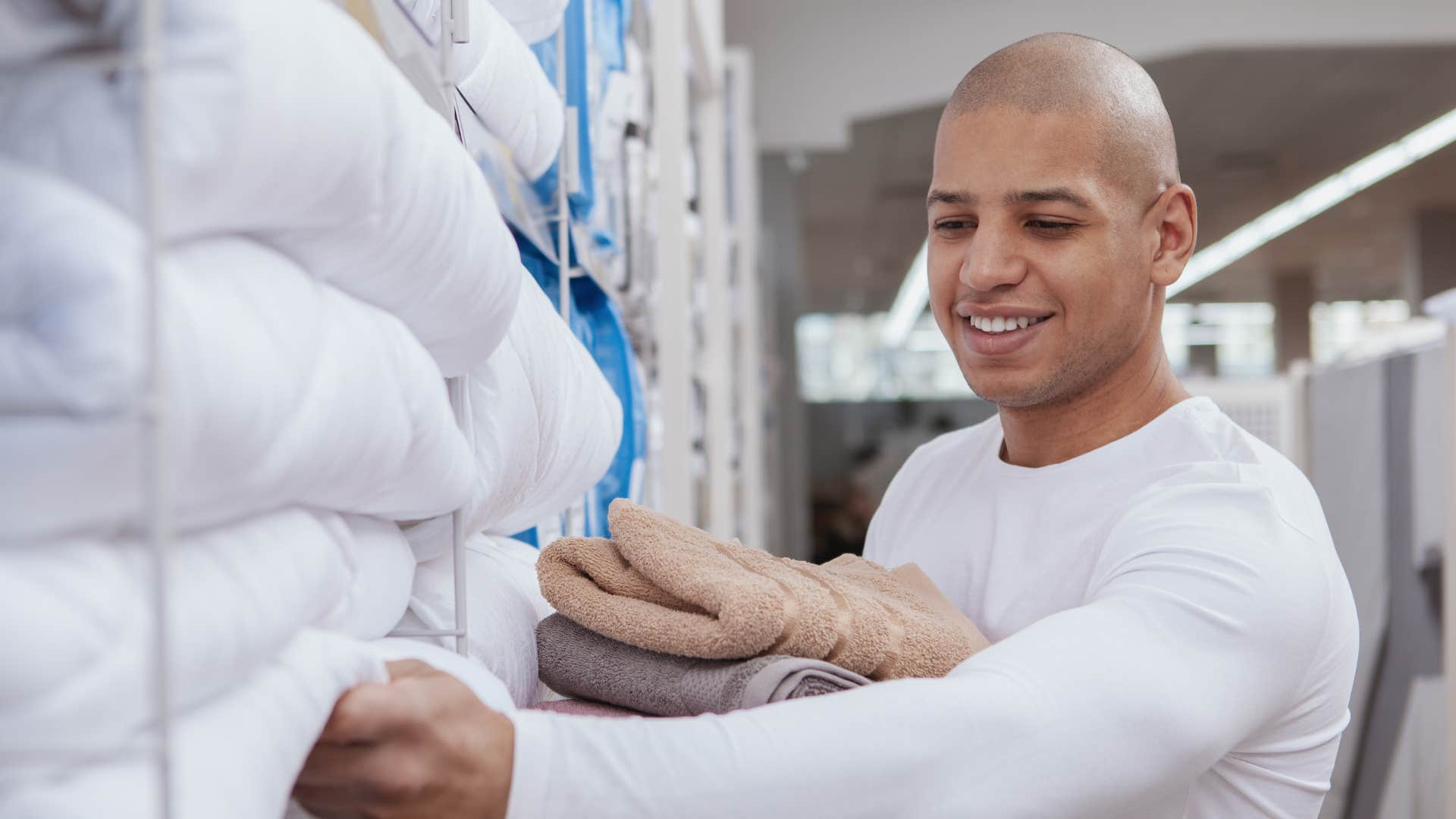 man looking for new accessories for his bedroom as he picks out pillow