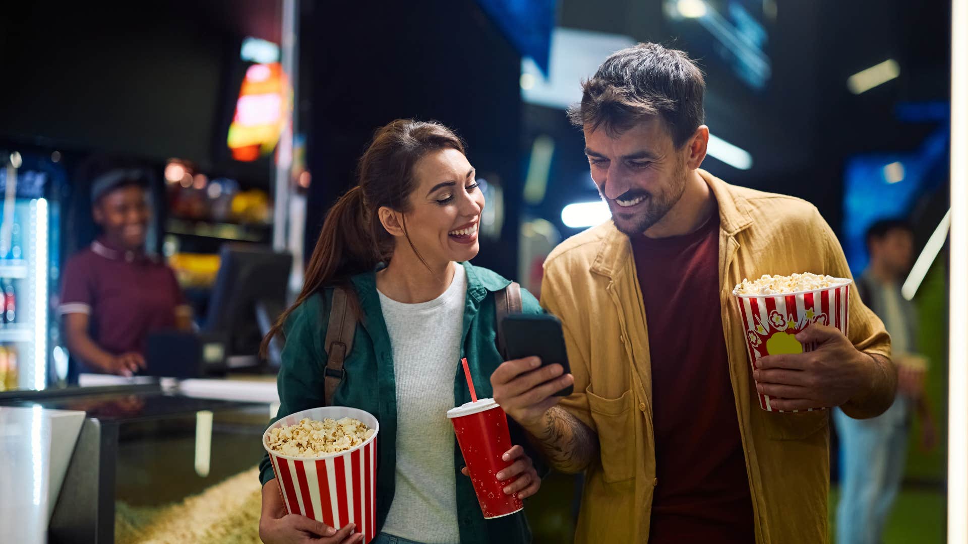 couple buying tickets and looking at phone as they head to watch movie