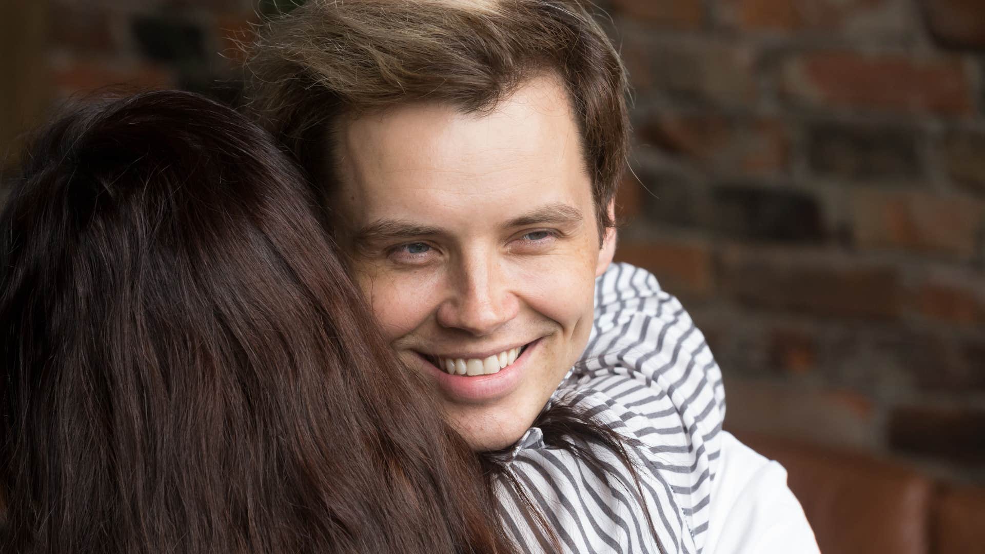 man forcing smiling while hugging woman