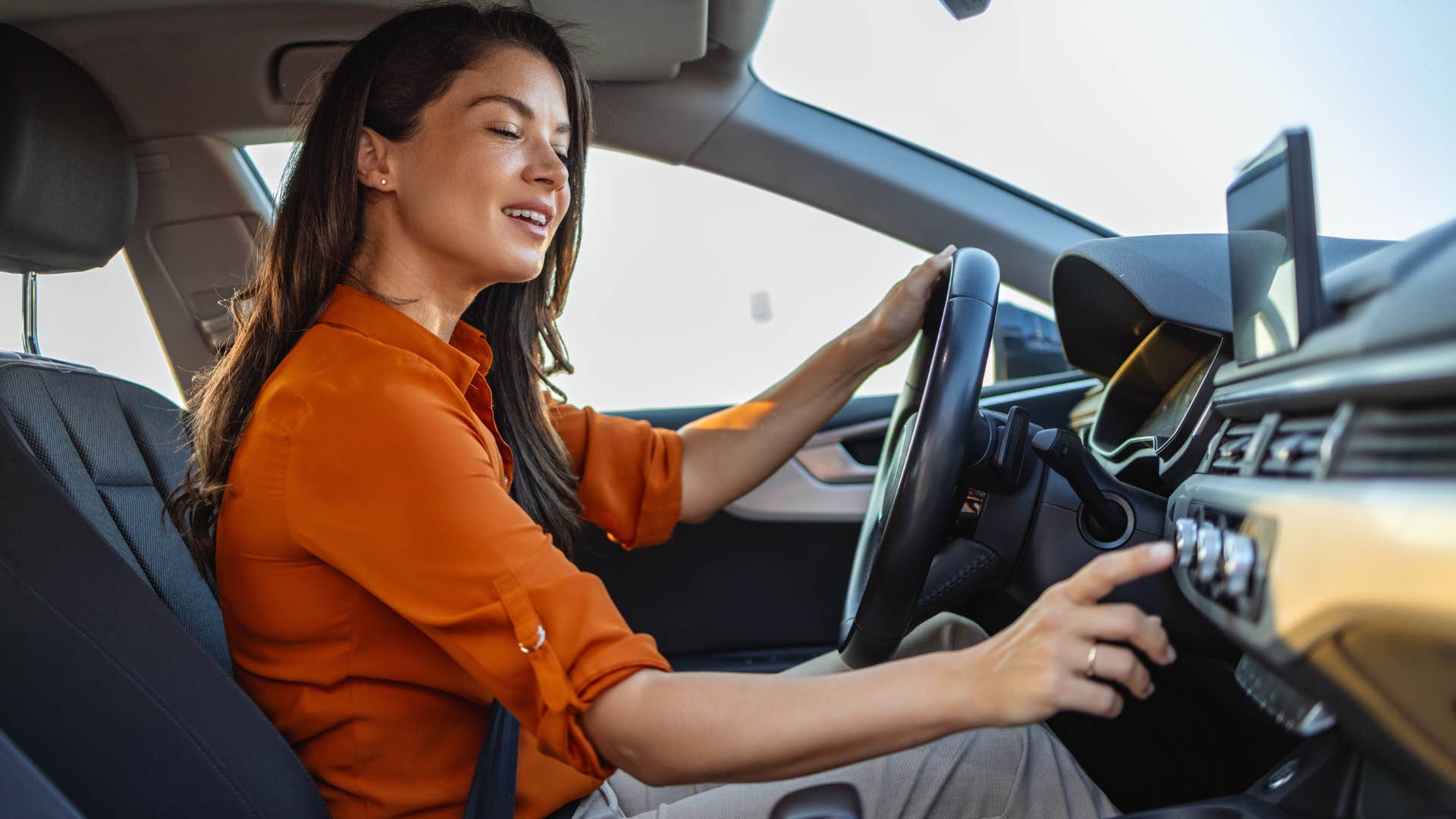 woman in orange shirt messing with ac as it has problems