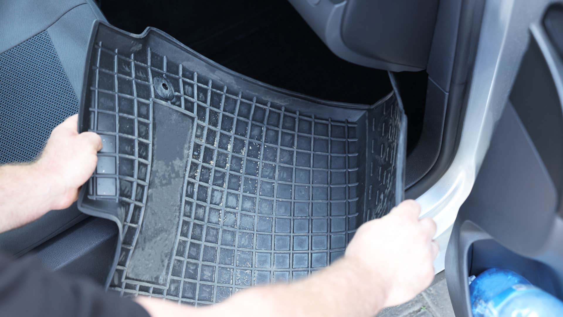 man picking up dirty mat they haven't cleaned in a while