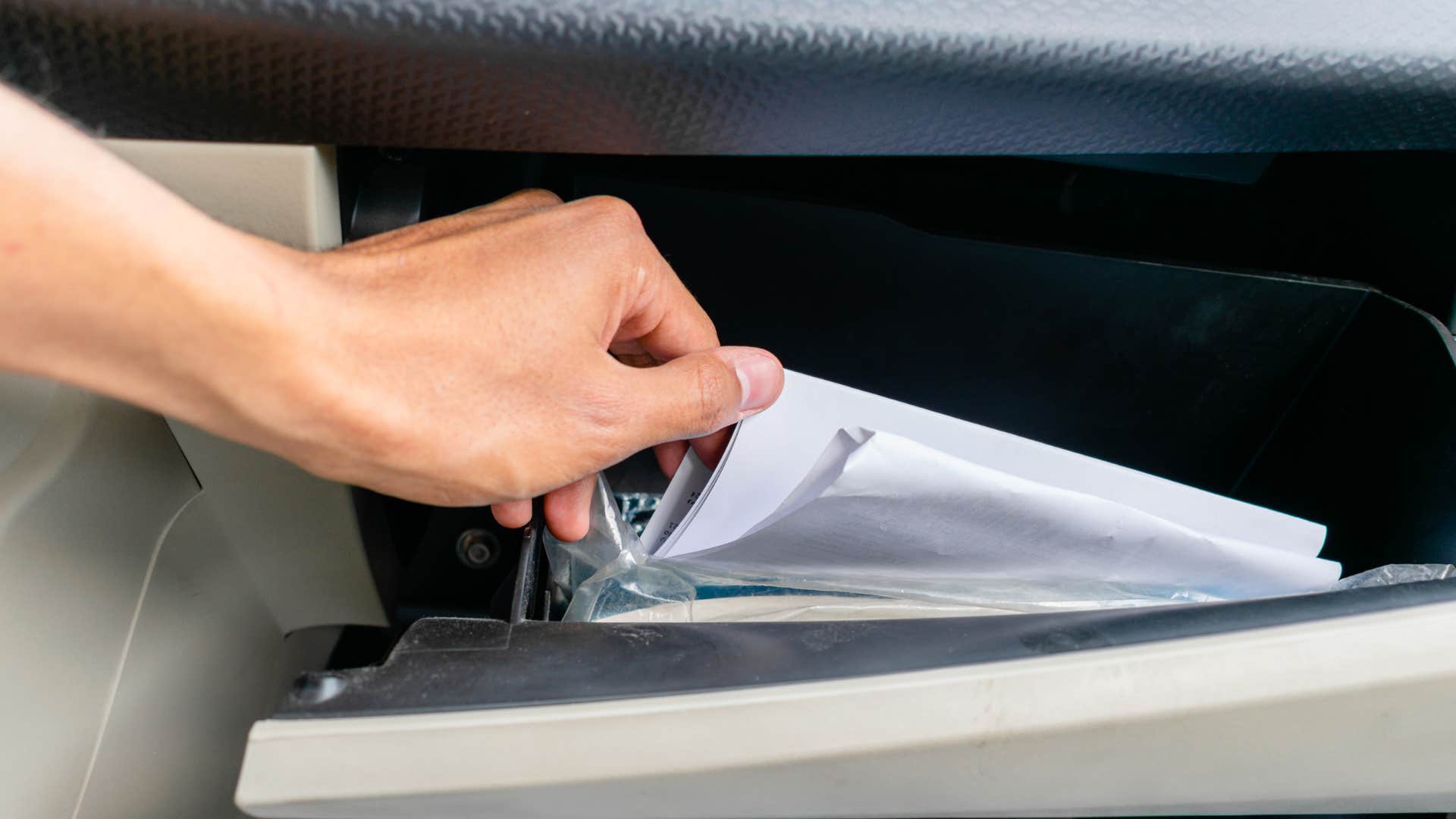 person hand sifting through disorganized glove box 