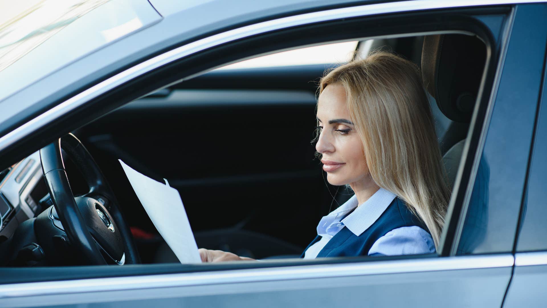 woman in. the car with documents in her hand