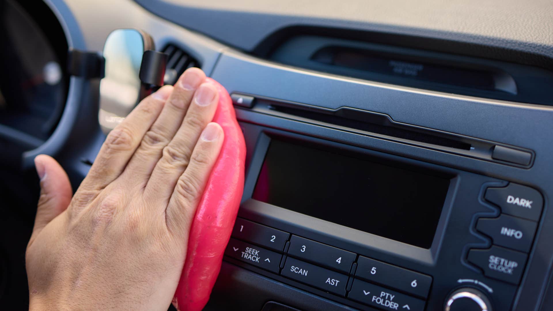man wiping dust away as it's everywhere in their car