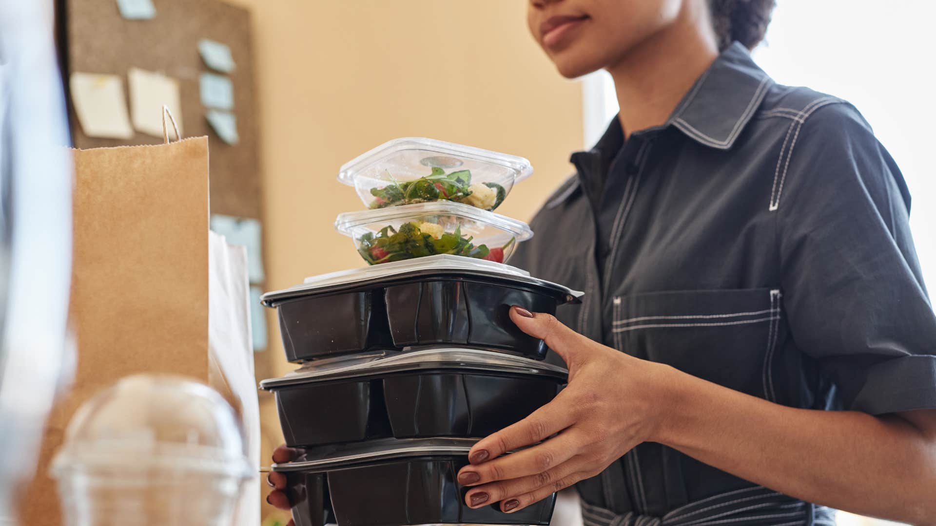 woman carrying piles of takeout containers