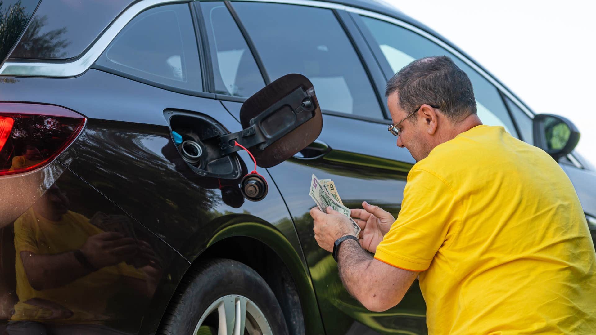 man in yellow filling gas tank as it's nearly always on empty