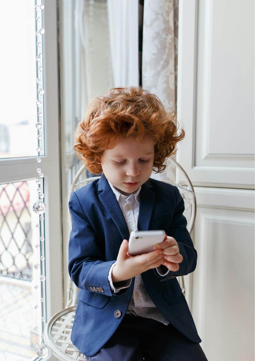 little boy in primary school on his phone