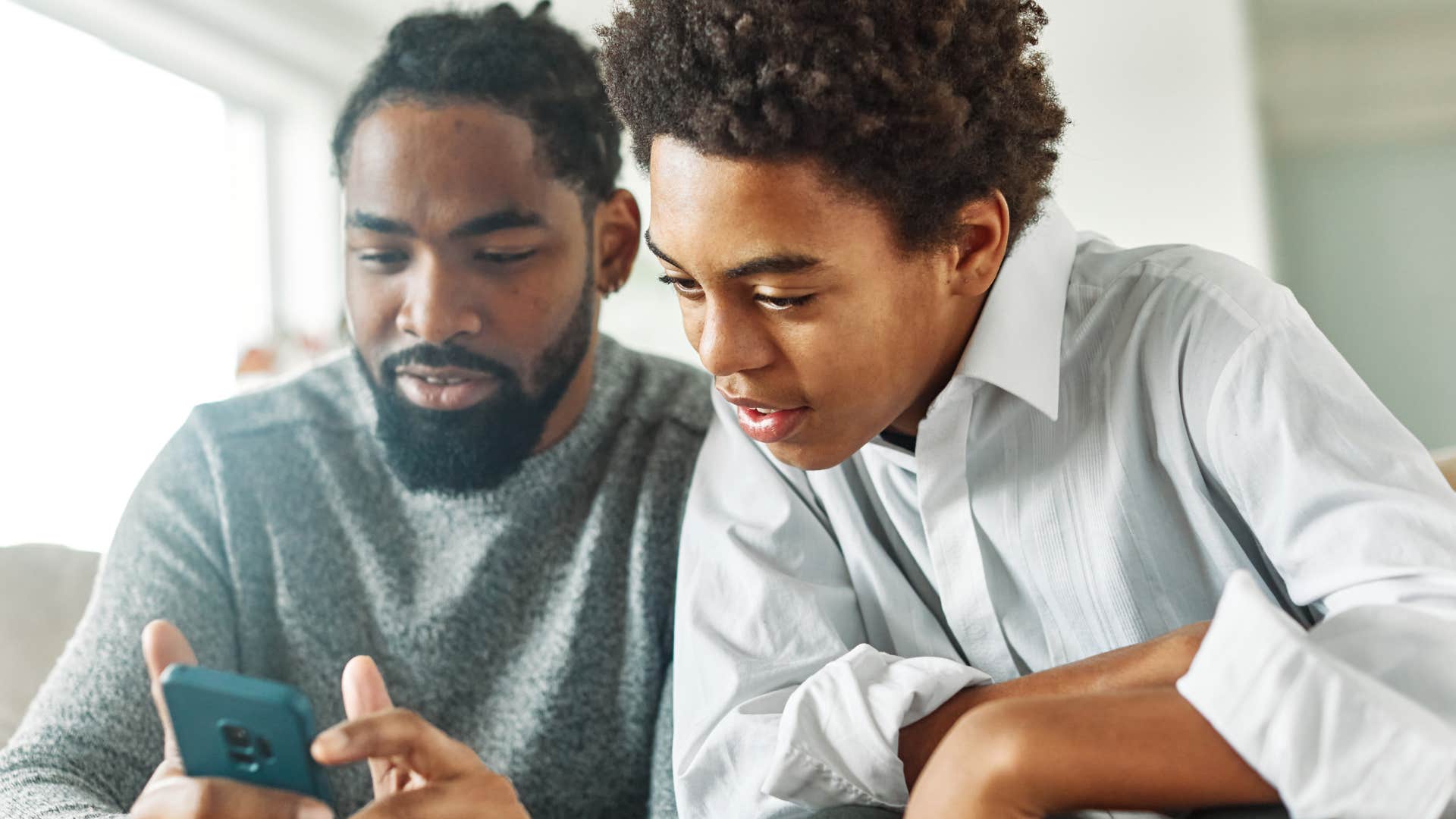 dad watching a video on his phone with his son