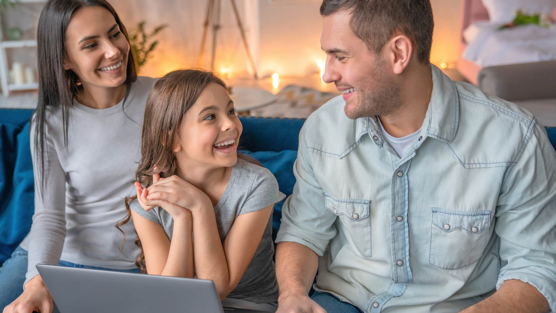 parents smiling sitting with their daughter on the computer