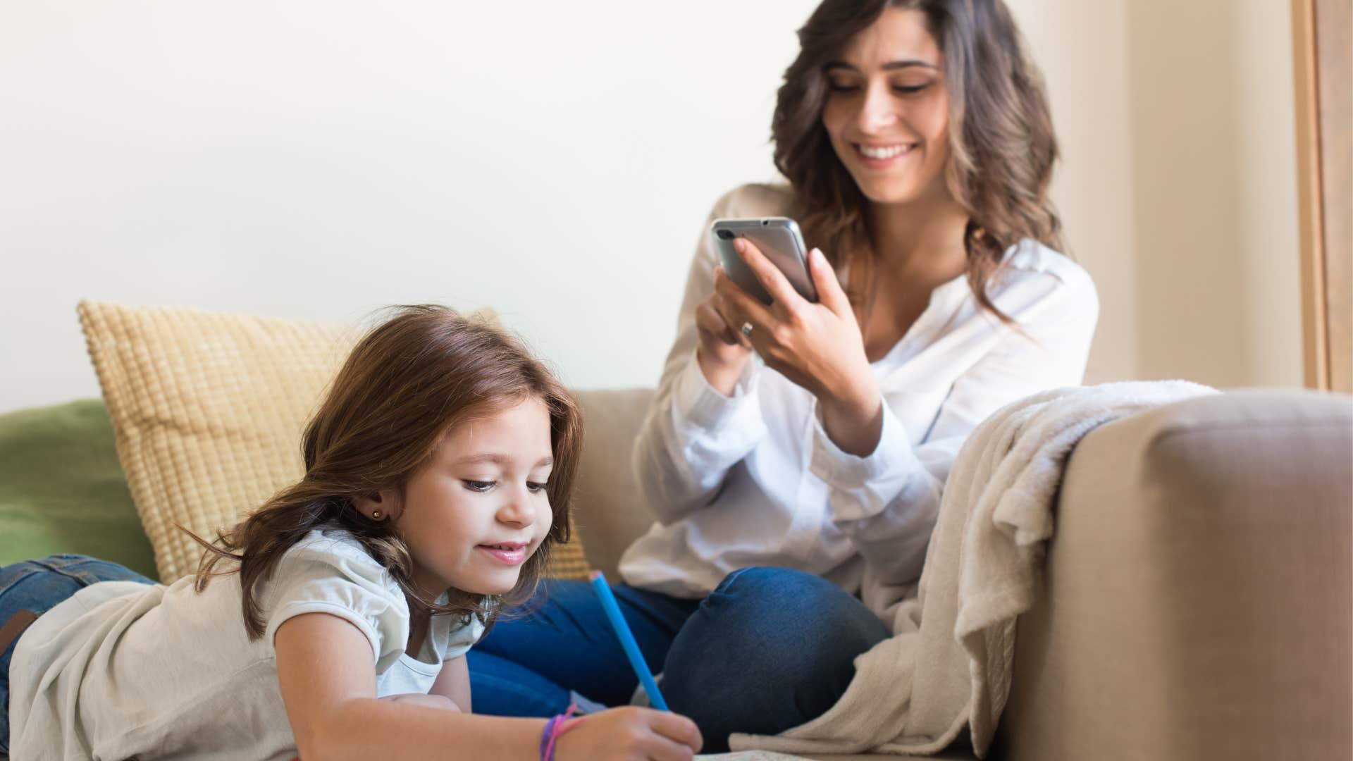 smiling mom with low self-esteem filming her daughter