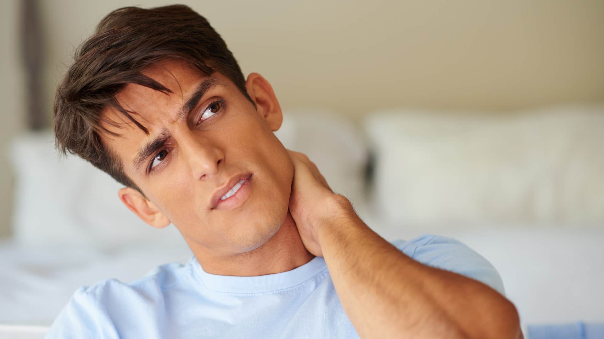 man feeling tense touching his neck