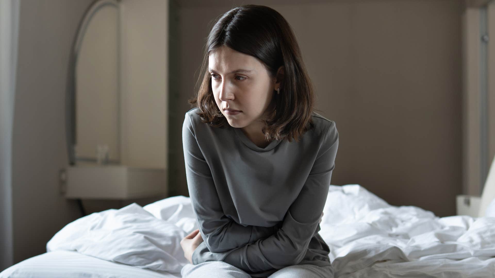 woman sitting on bed upset