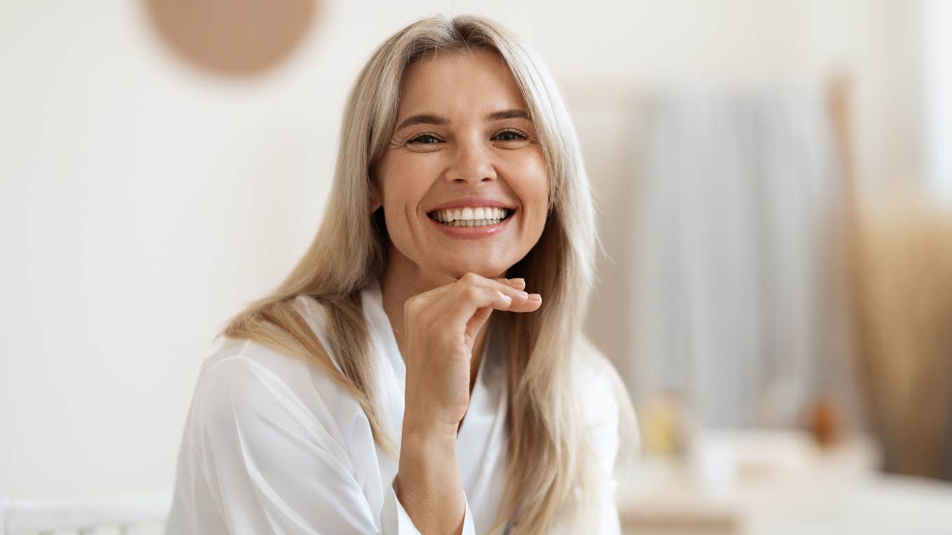 smiling woman sitting in a robe in the bathroom without her phone