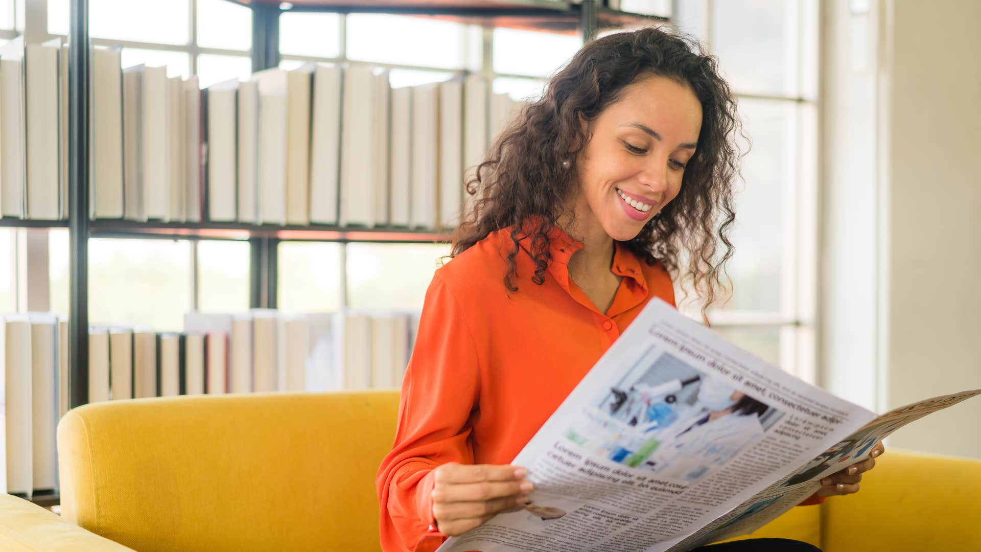 woman in red reading newspaper as she believes curated content beats the algorithms 