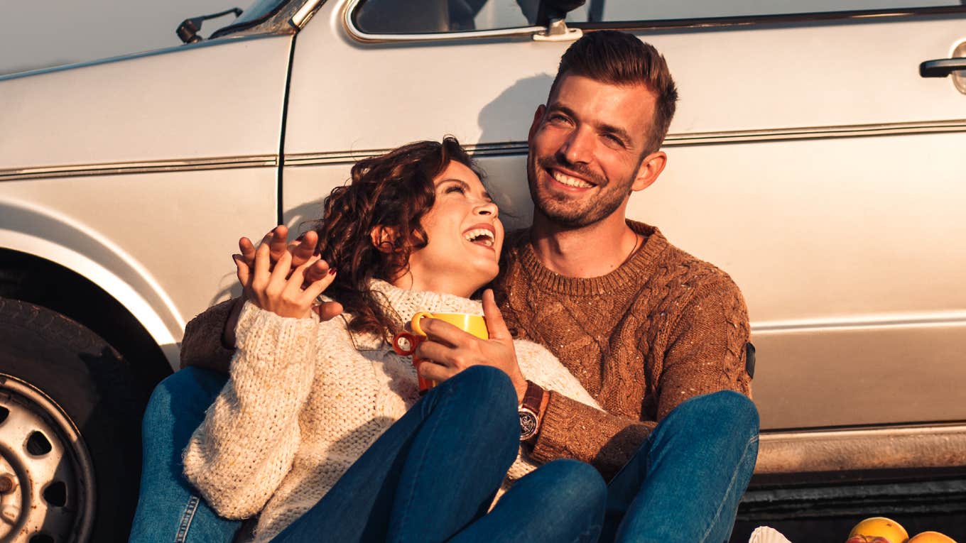 Young couple enjoying a sunset picnic by an old-fashioned car showing how people in their thirties love differently than those in their twenties.