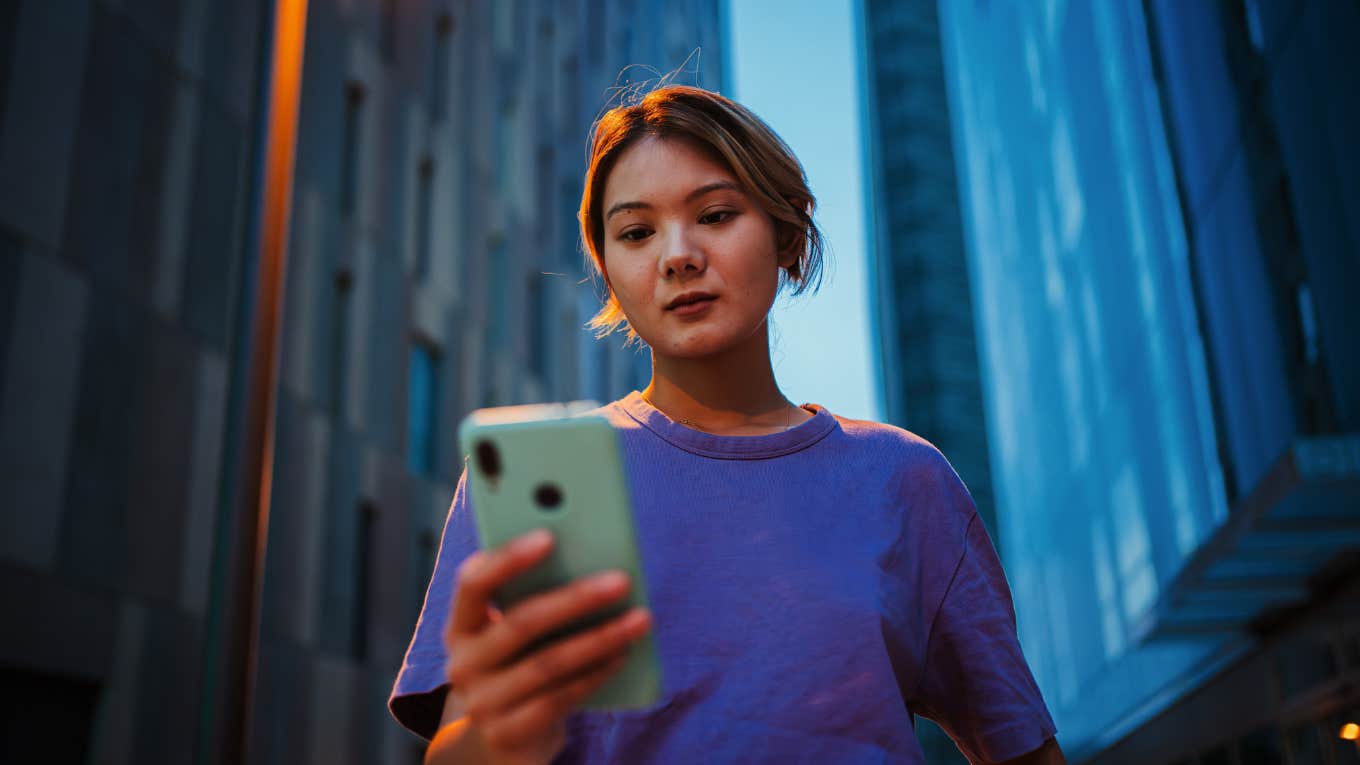 woman standing outside looking at her phone