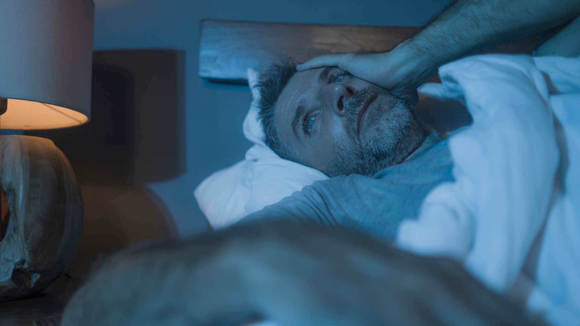 worried man lying in bed thinking about messiness