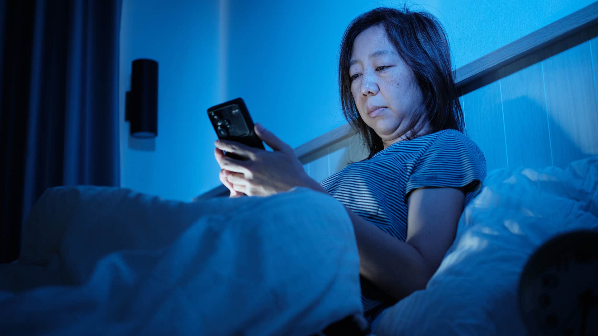 worried woman on her phone in bed thinking about not having time to decompress
