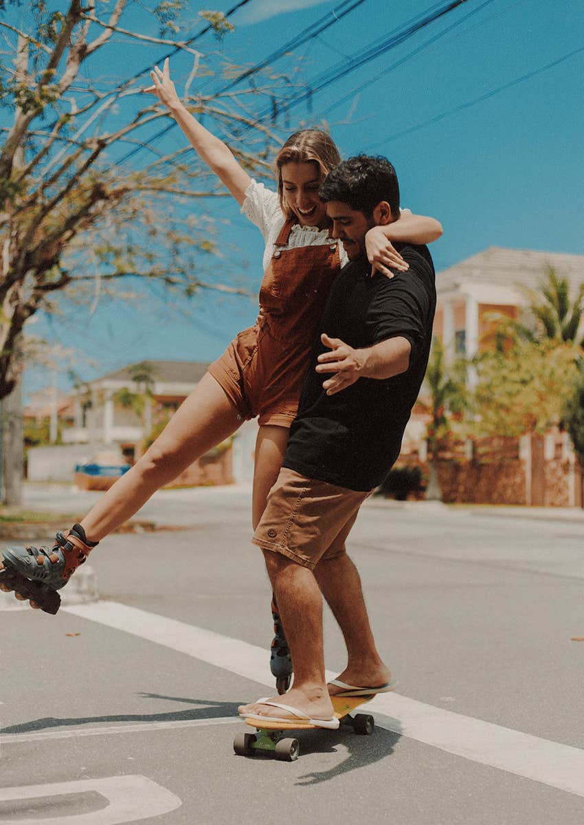 playful and happy couple on skateboard and roller skates