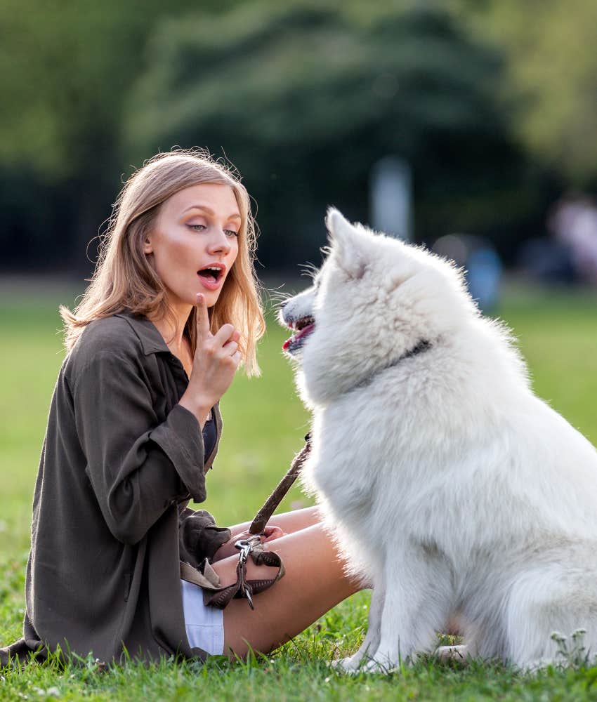 woman giving command to dog at park