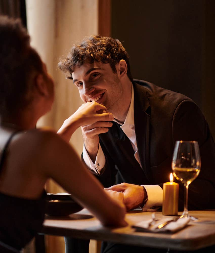 man charming woman on date by kissing her hand