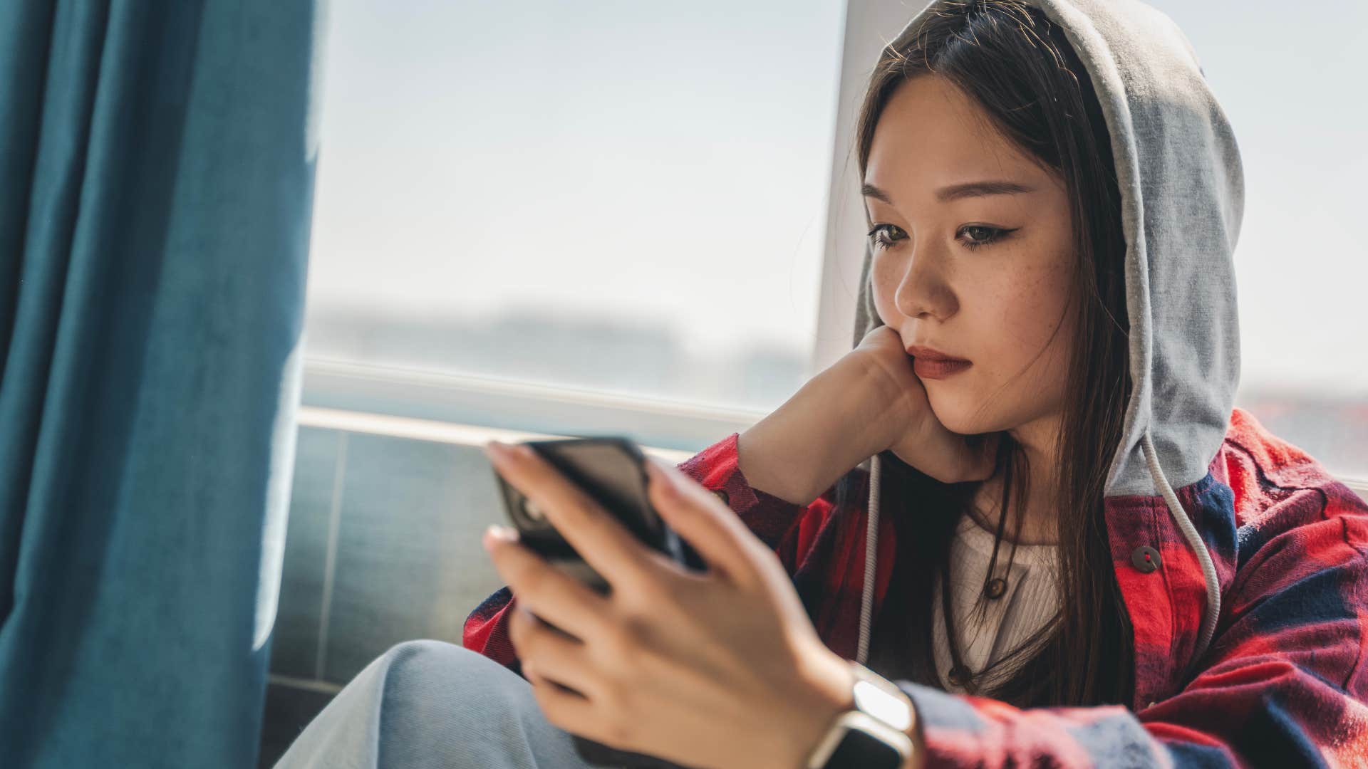 exhausted Gen Z woman looking at her phone