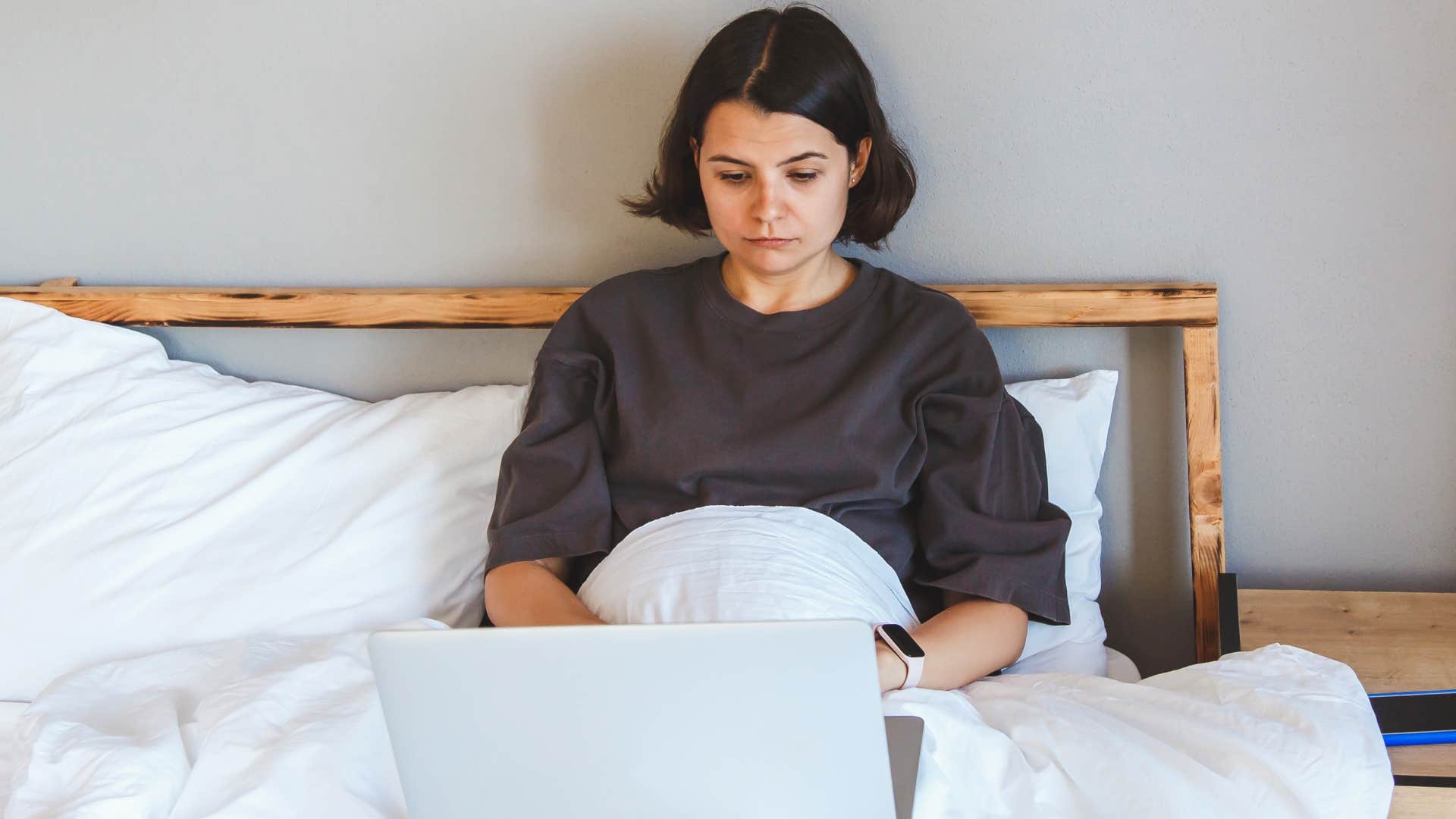 woman who feels pressured to work at home sitting in bed
