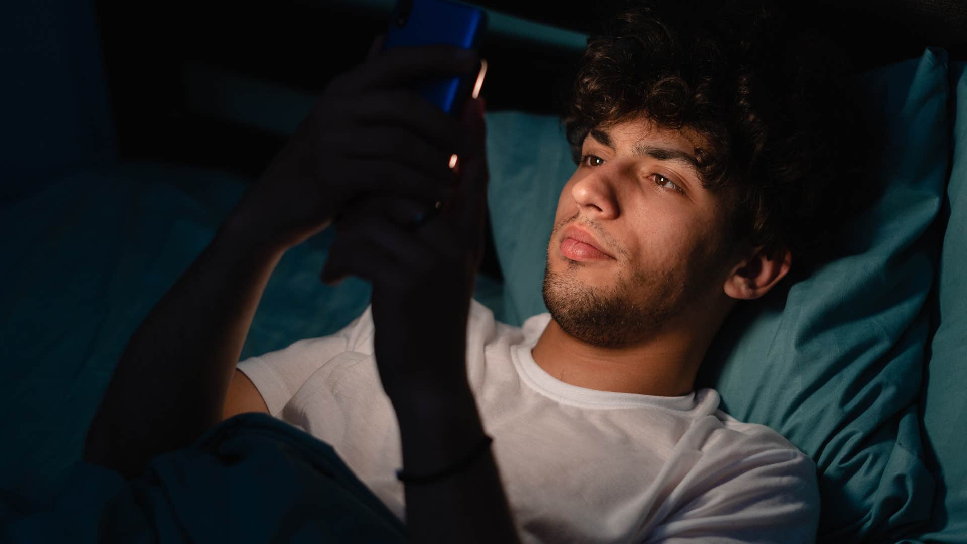 gen z man on his phone in bed not getting good sleep