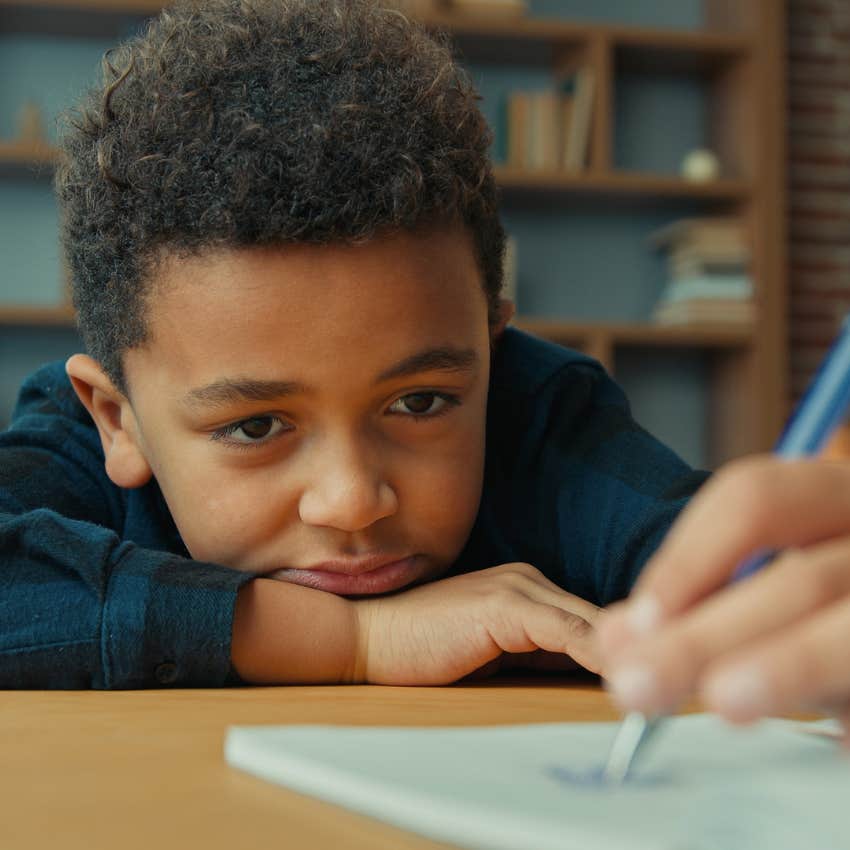 little boy writing by hand at school