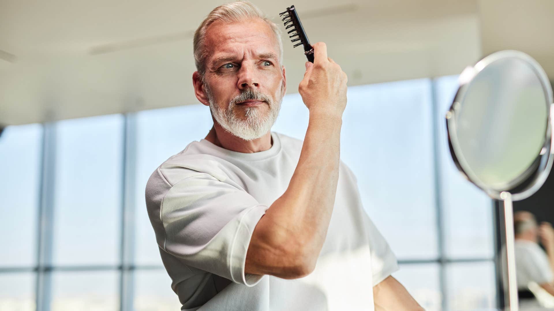 self-centered man doing his hair in the mirror