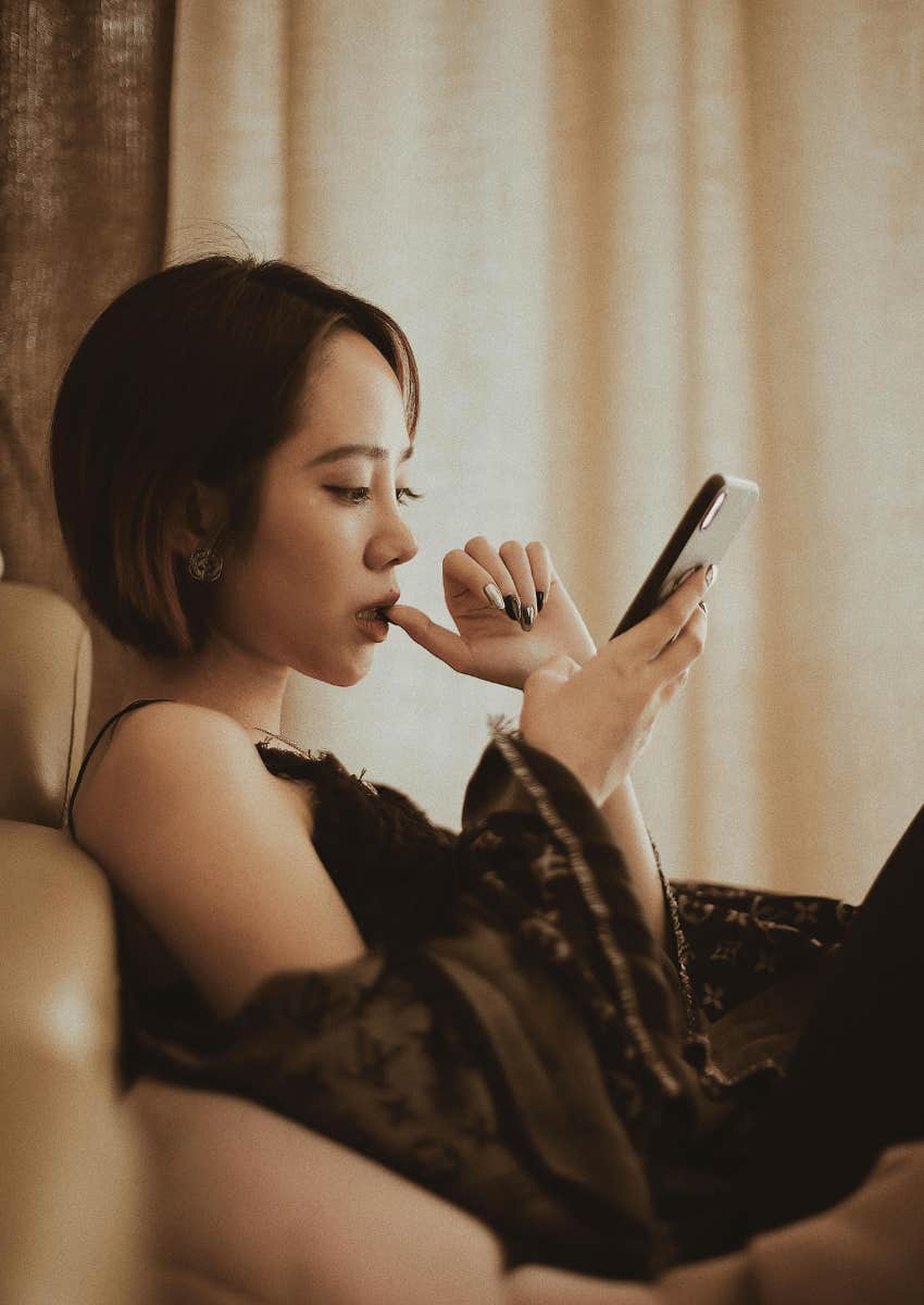 serious young woman staring down at phone