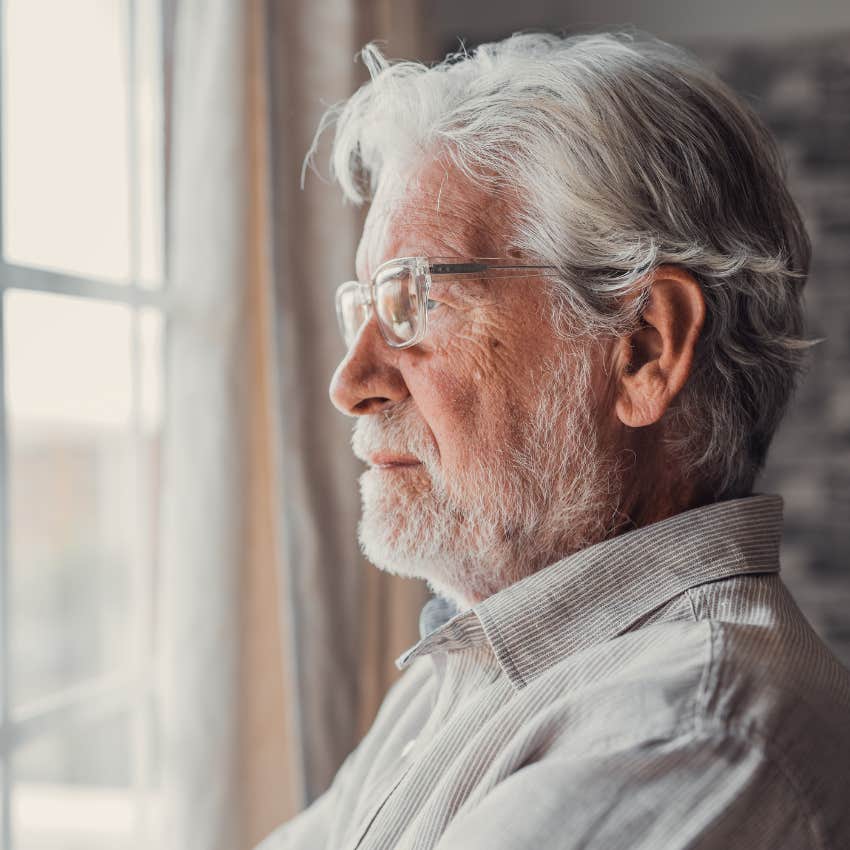 quiet and emotionally distant man looking out window at home