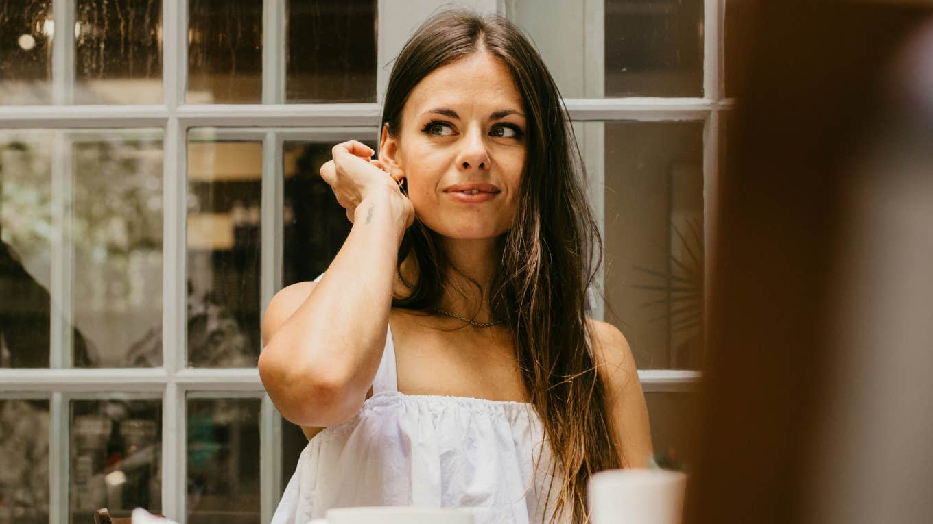 Woman sitting with friends while feeling detached and uncomfortable showing the signs you’ve outgrown your social circle and are ready to move up in life.
