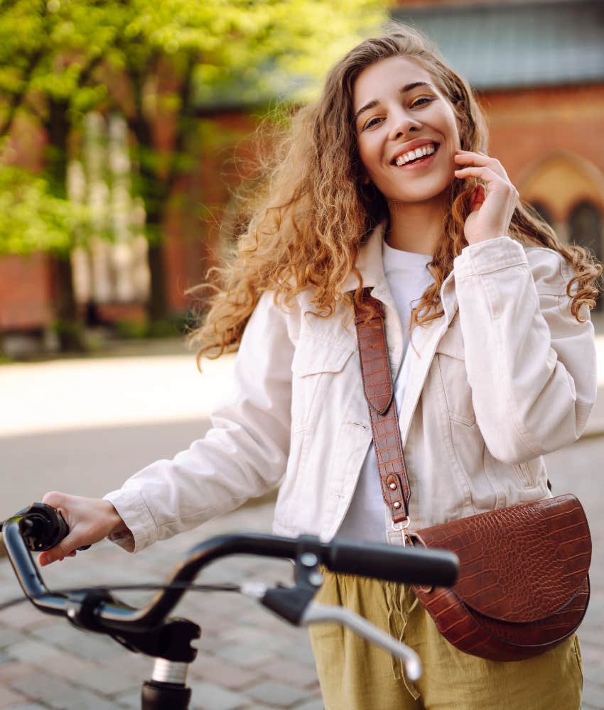 Smiling person with bicycle showing they are not dying and getting over heartbreak