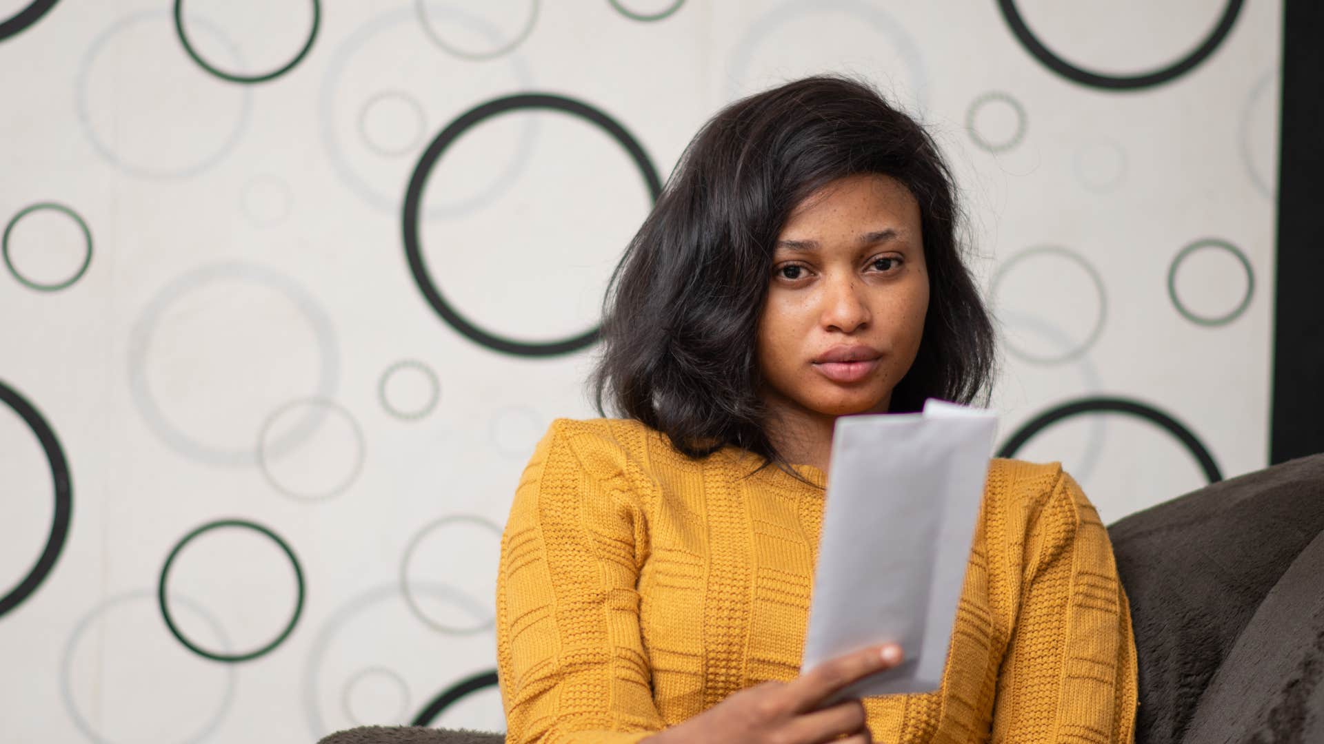 sad woman looking at unopened mail at home
